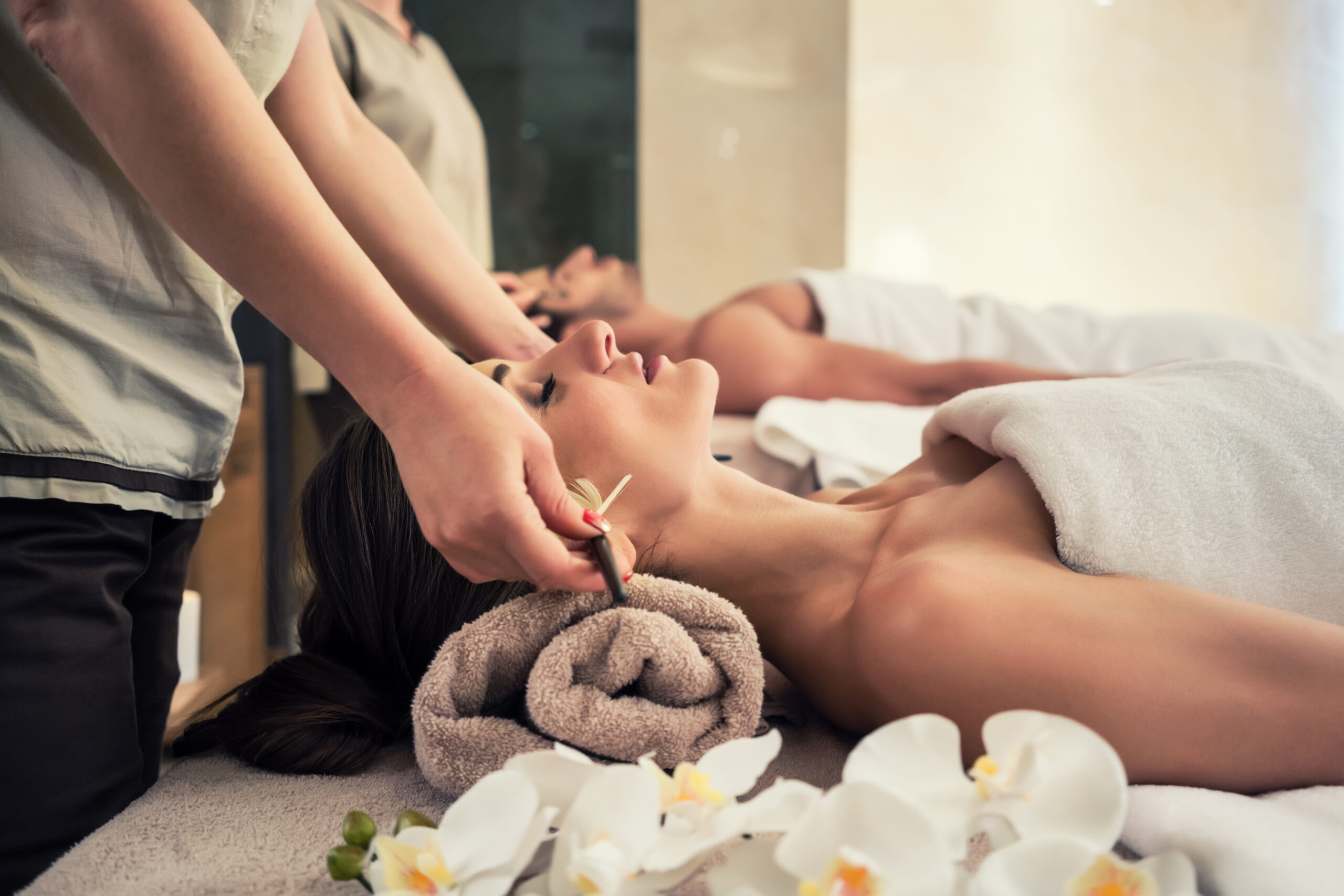 Relaxed woman lying down on massage bed during facial treatment at Asian spa and wellness center