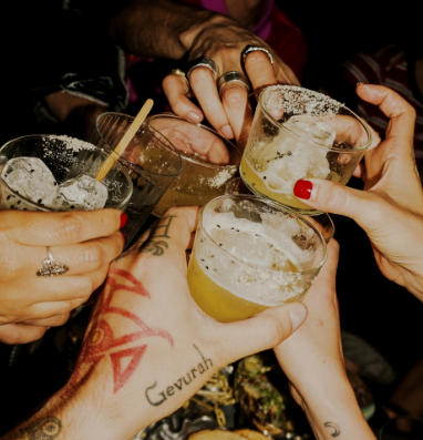 Manos brindando con coctéles de uno de los mejores bares de la CDMX llamado El Desconocido.